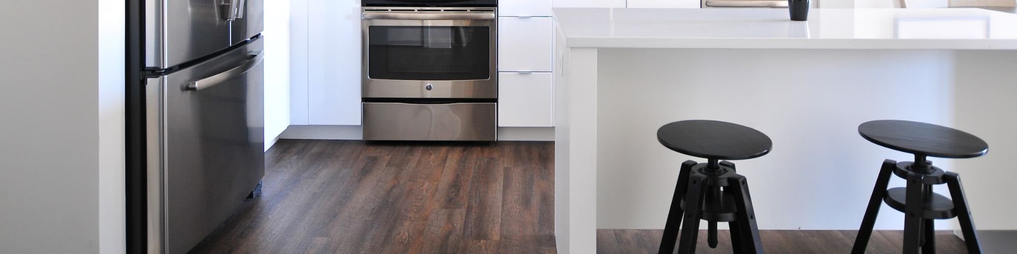 white kitchen island with black chairs and brown hardwood flooring from Johnson & Sons Flooring in Knoxville, TN